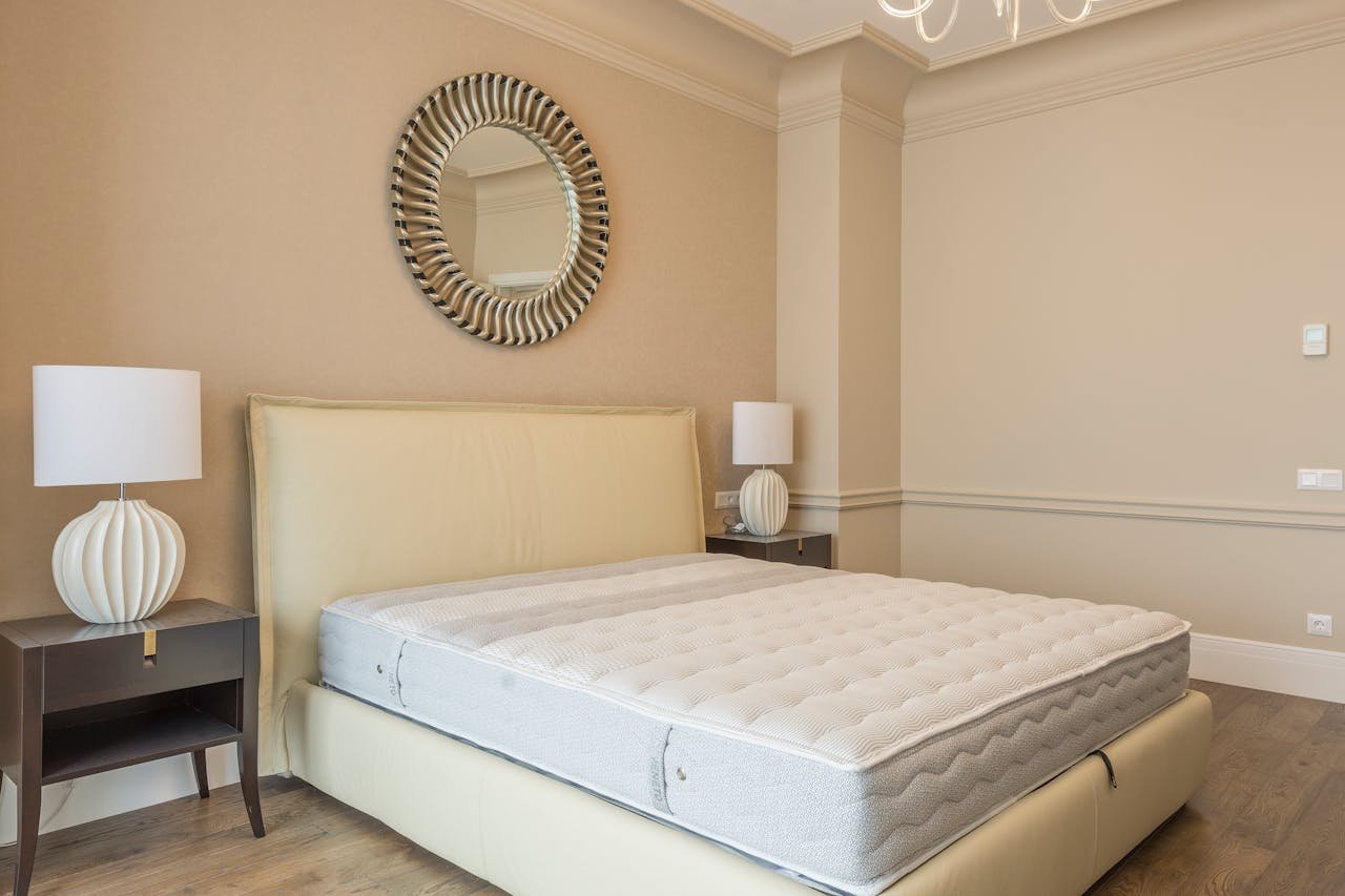 Spacious bedroom featuring modern decor, elegant lighting, and a plush bed with neutral tones.