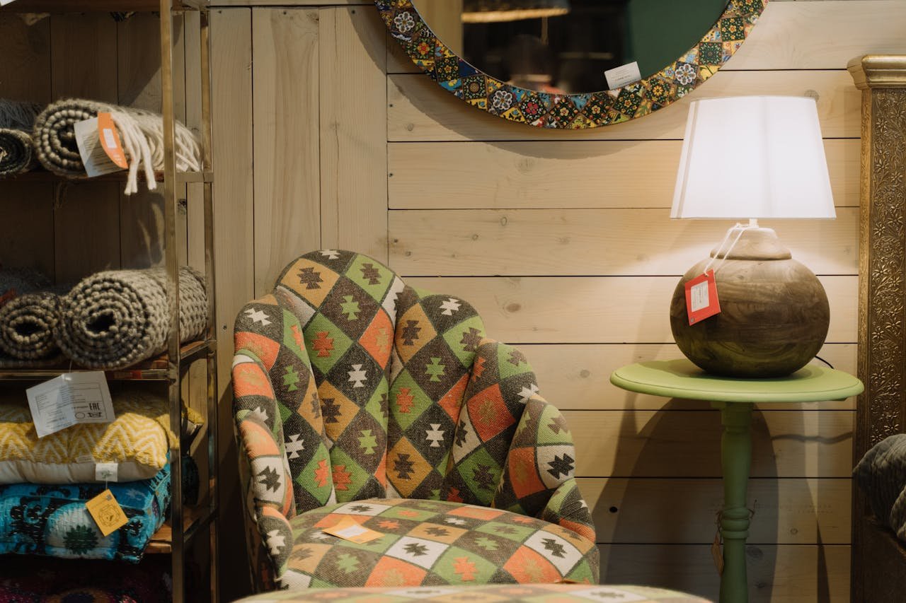 Comfortable armchair with colorful geometric patterns in a cozy, well-decorated interior space with lamp and textiles.